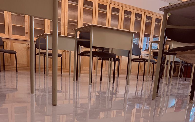 Salle de classe vide avec des tables et des chaises en bois sur un sol brillant, vue d'un angle bas