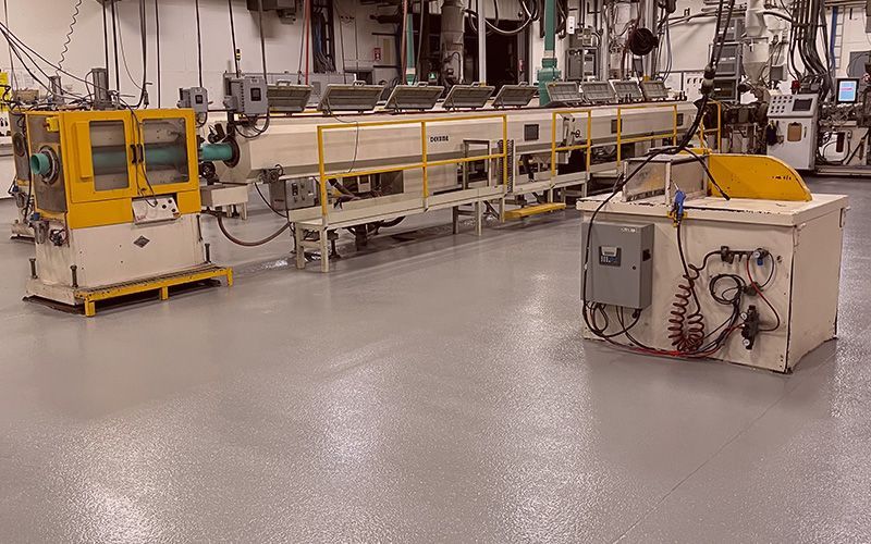 Atelier industriel avec des machines jaunes et une longue chaîne de convoyage sur un sol brillant