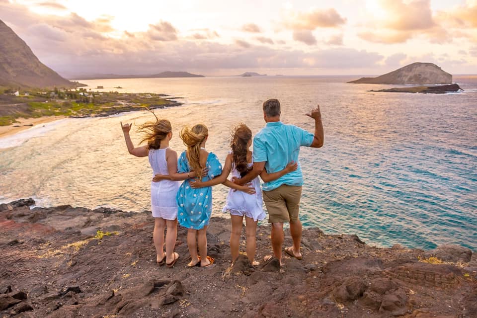 A family is standing on top of a cliff overlooking the ocean.