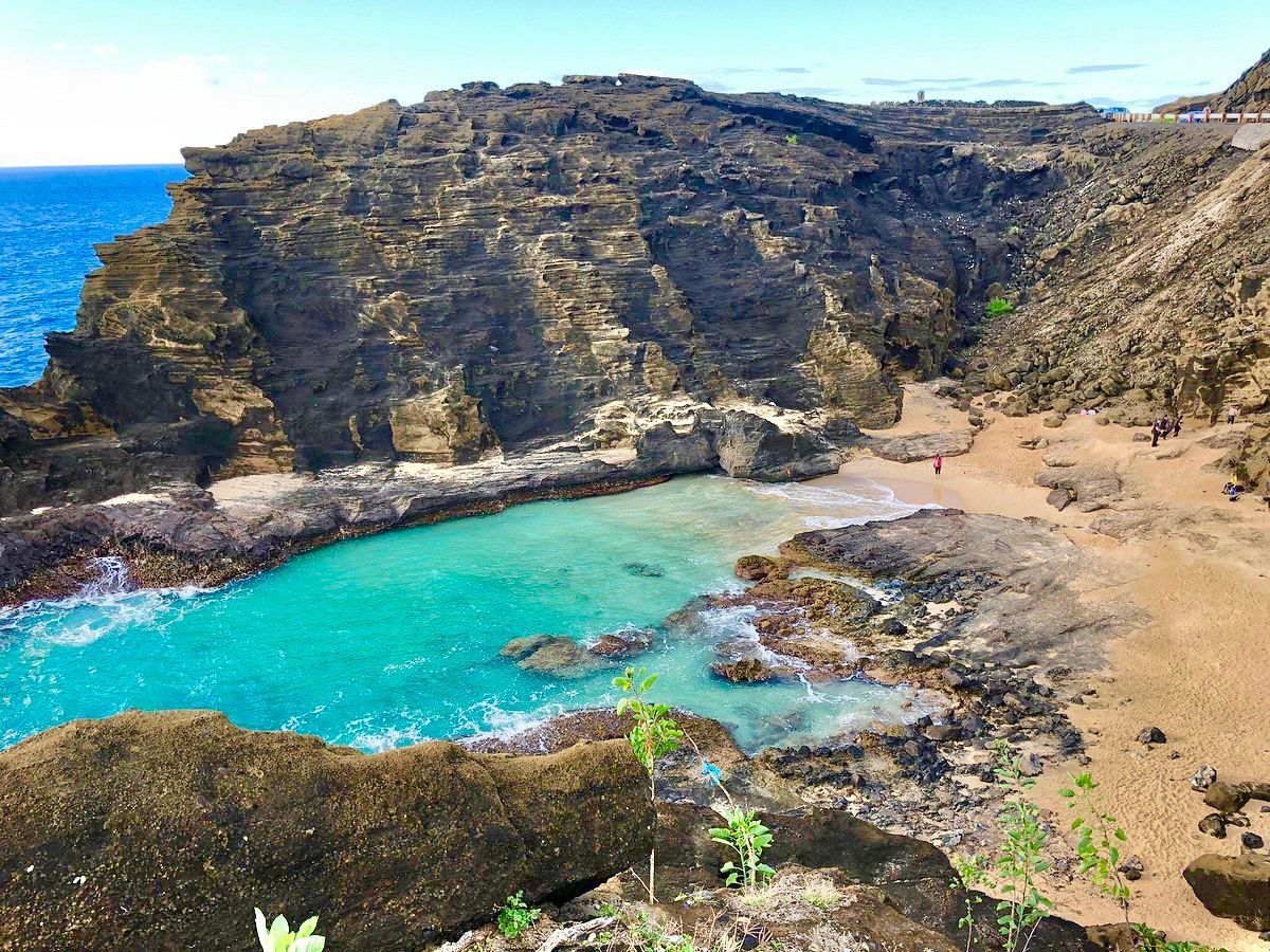 A small body of water surrounded by rocks and cliffs next to the ocean.