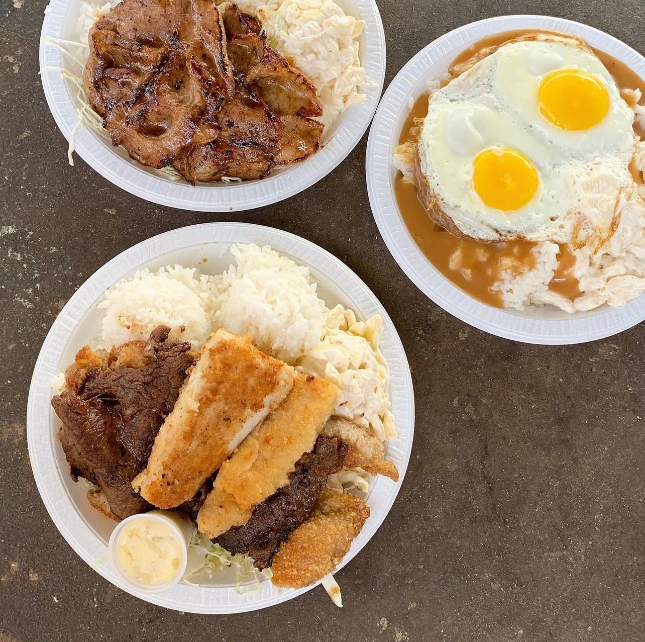 Three bowls of food with rice and eggs on a table