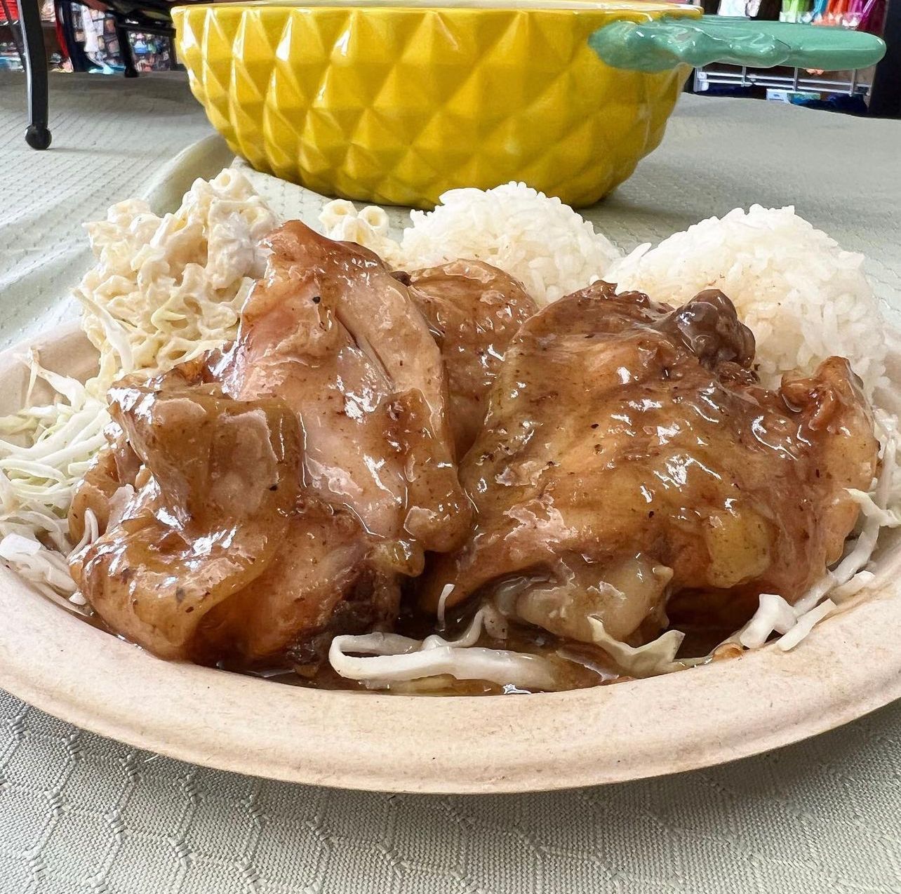 A paper plate topped with chicken noodles and sauce