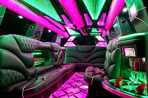 The inside of a limousine with pink and green lights.