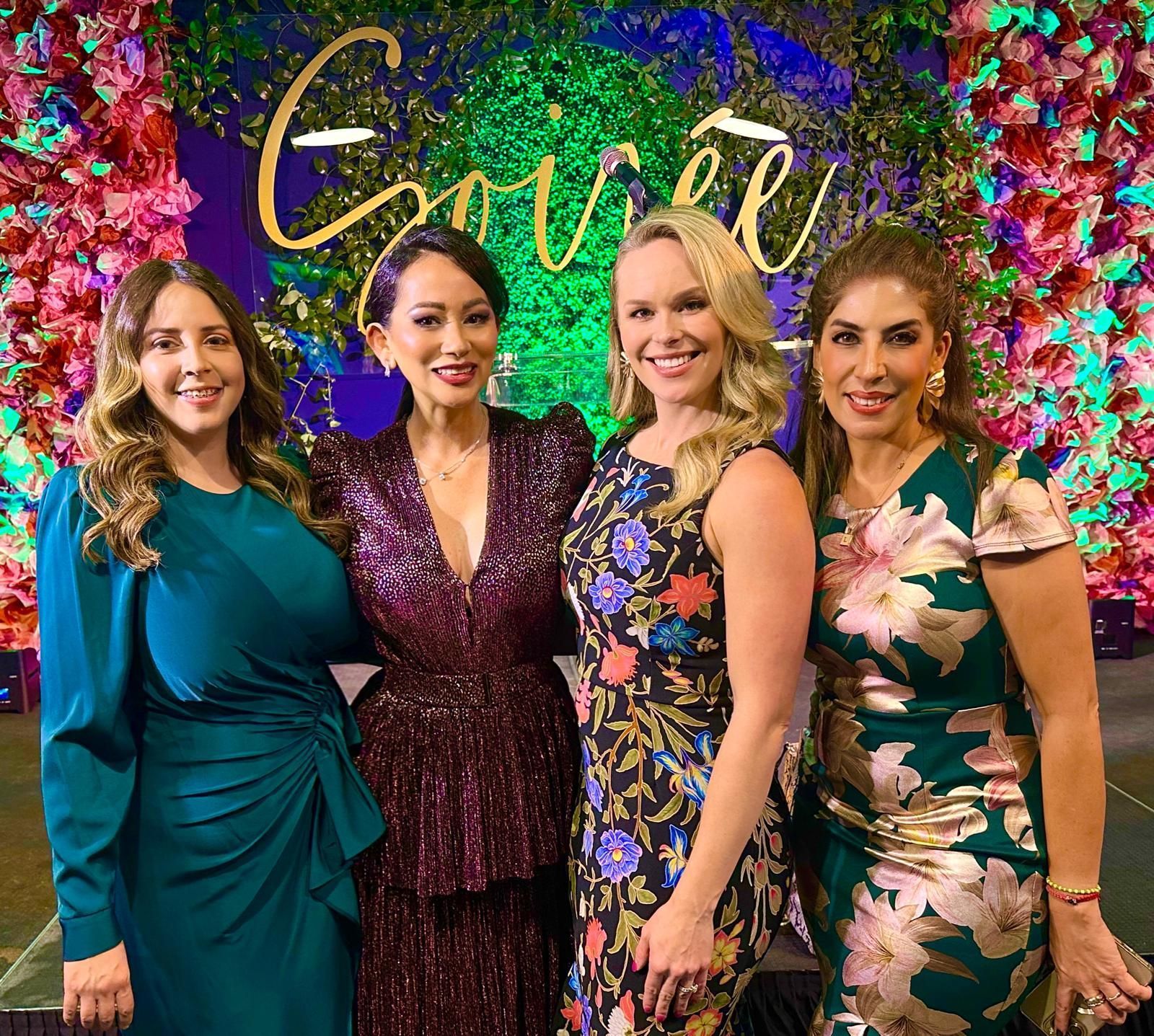 A group of women in dresses are posing for a picture.