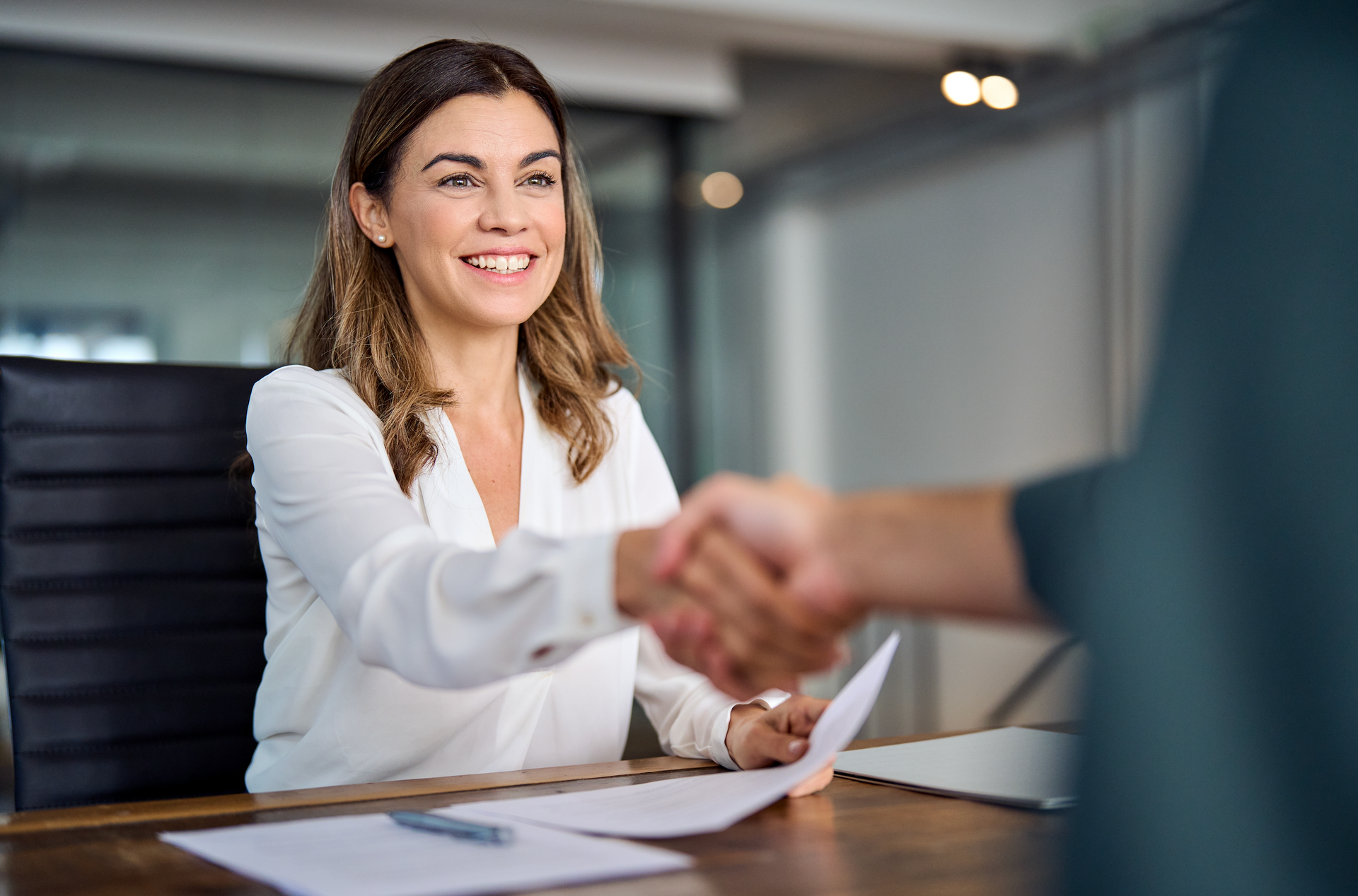 A woman is shaking hands with a man at a table.