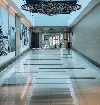 Modern hotel lobby hallway with glossy marble floor, abstract wall art, and sculptural ceiling decor