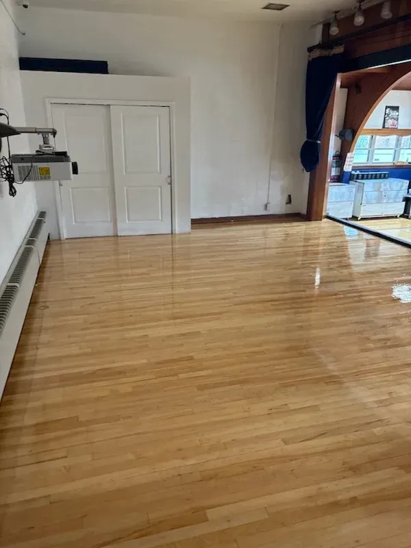 Empty white room with dark wood floors, built-in bench, and a large window nook