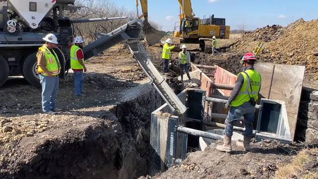 Construction workers pouring concrete from a Volumetric Mixer truck  at a civil construction site . 