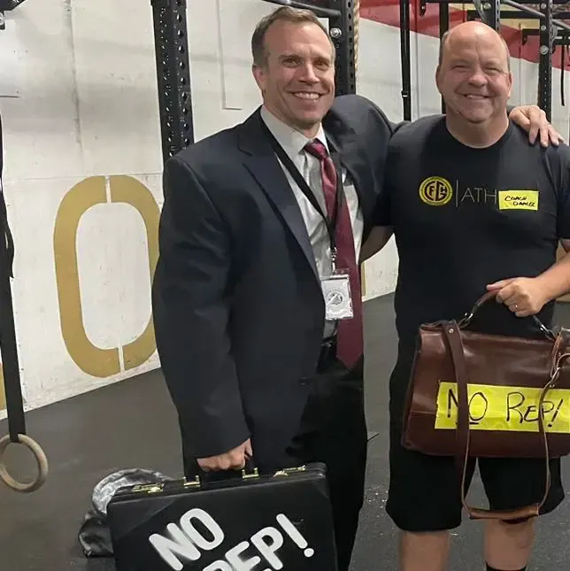 A man in a suit holds a briefcase that says no rep