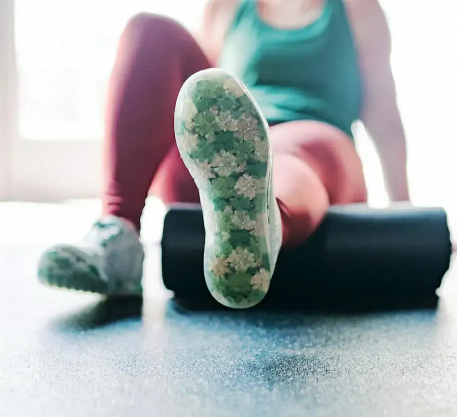 A woman is sitting on a foam roller with her legs crossed.