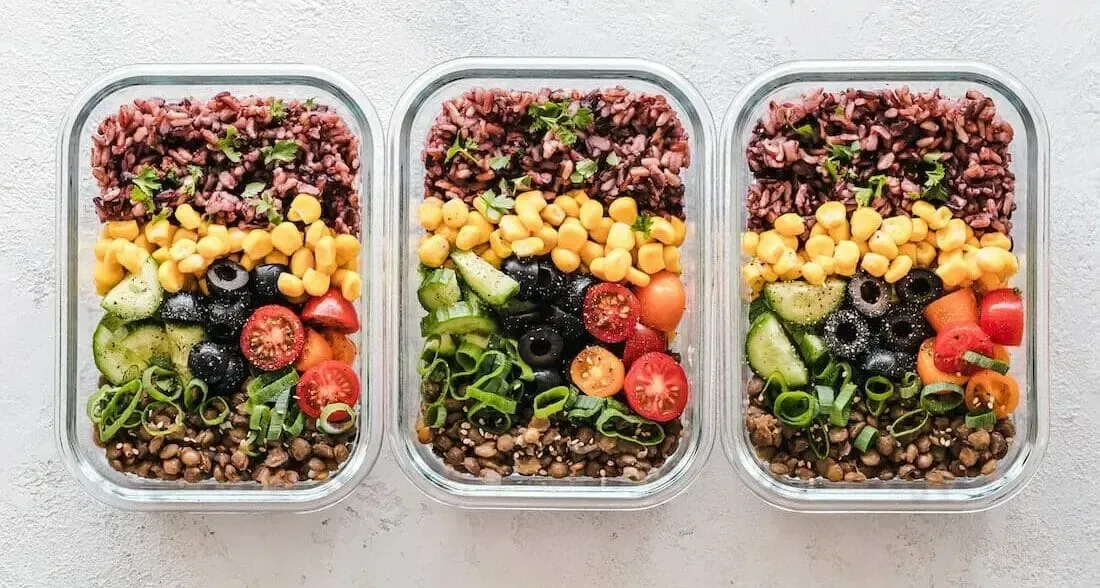 Three glass containers filled with different types of food on a table.