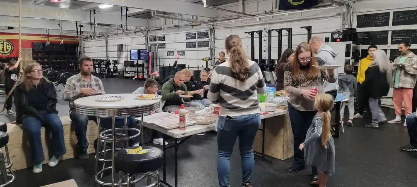 A group of people are standing around tables in a gym.