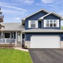 A blue house with white shutters and a white garage door.