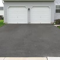A driveway leading to a garage with two white garage doors.