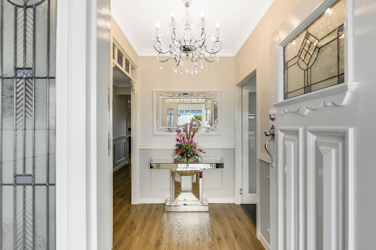 A Hallway in a House With a Table and a Chandelier — Windamere Homes in Highfields, QLD