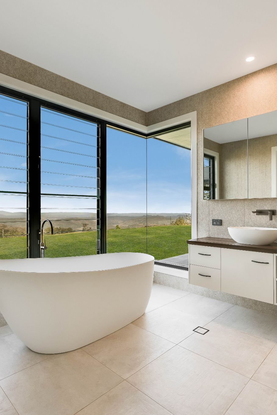 A Bathroom With a Tub, Sink, Mirror and Large Windows — Windamere Homes in Highfields, QLD