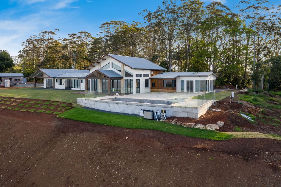 A Large House With a Pool in the Backyard is Surrounded by Trees — Windamere Homes in Highfields, QLD