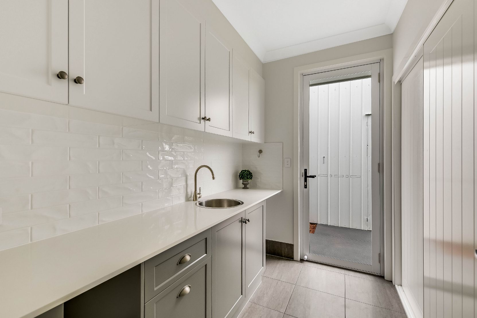 A Kitchen With White Cabinets, a Sink, and a Door — Windamere Homes in Highfields, QLD