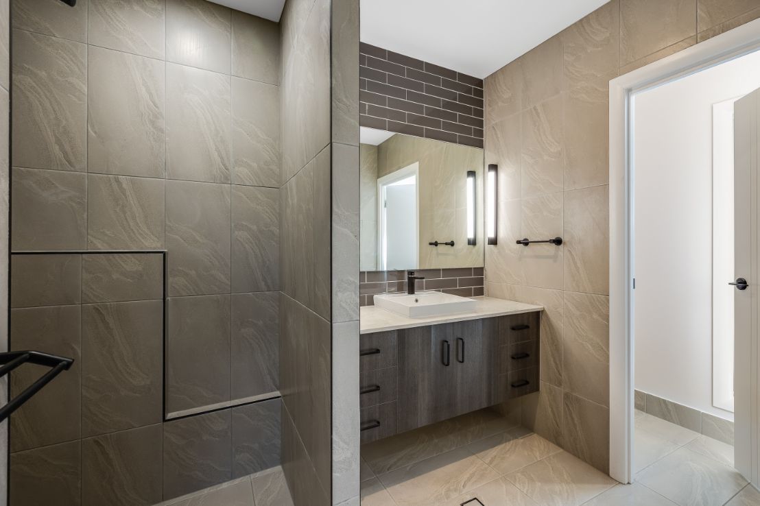 A Bathroom With a Walk in Shower, Sink and Mirror — Windamere Homes in Highfields, QLD