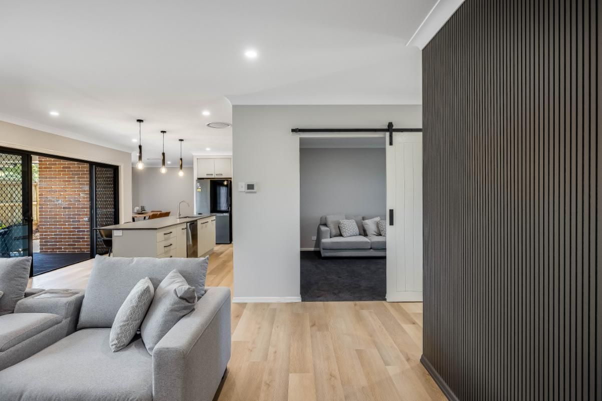 A Living Room With a Couch and Sliding Barn Door — Windamere Homes in Highfields, QLD
