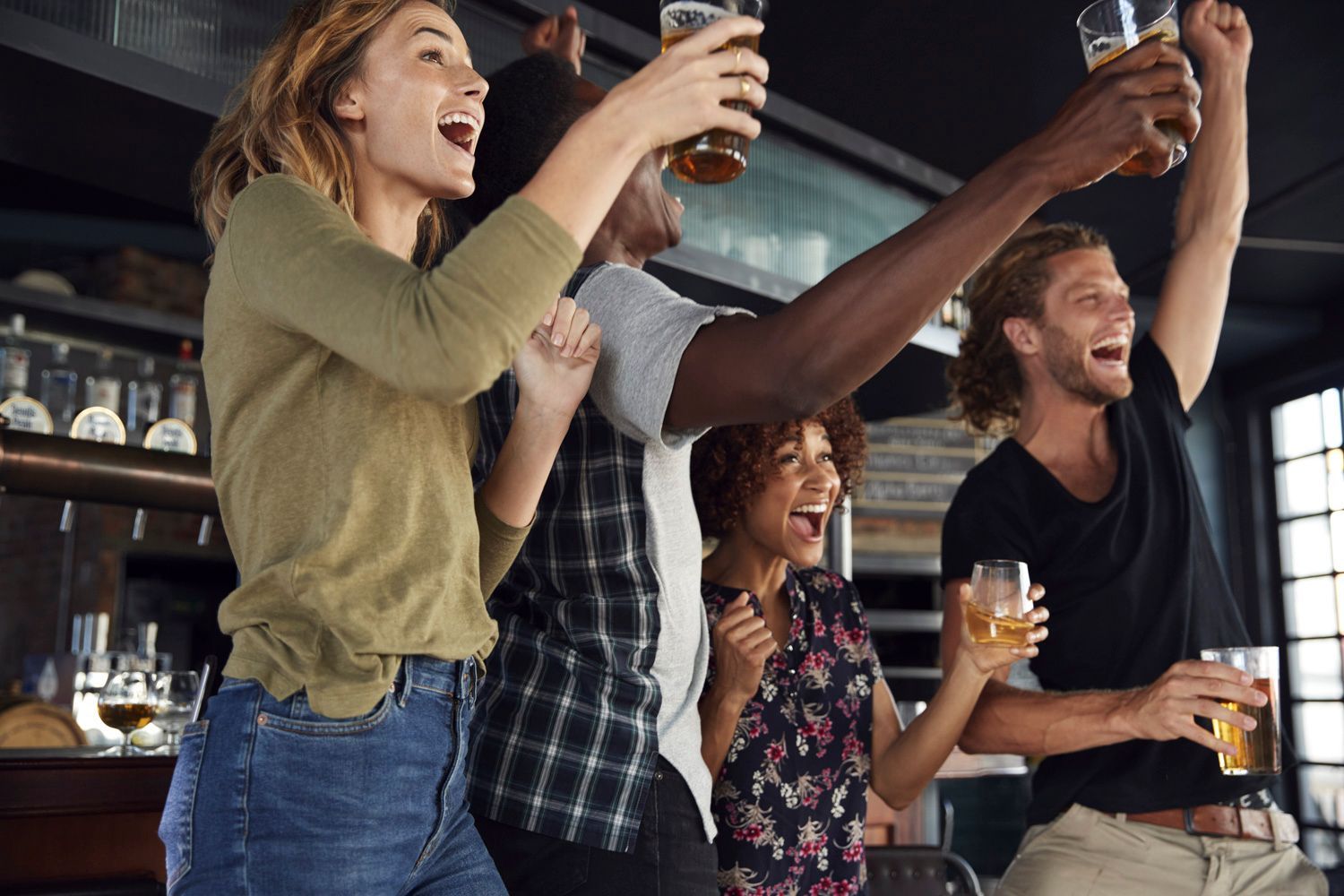 A group of people are toasting with beer in a bar.