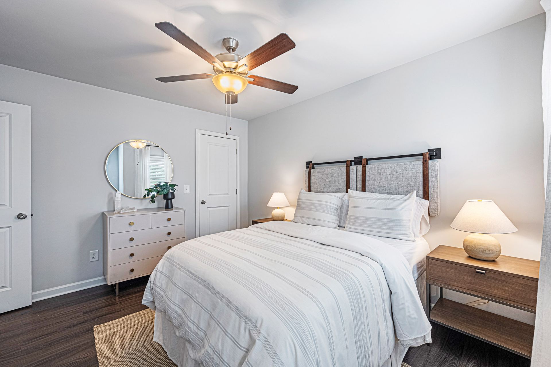 A bedroom with a bed , dresser , nightstand , mirror and ceiling fan at Collins Place.