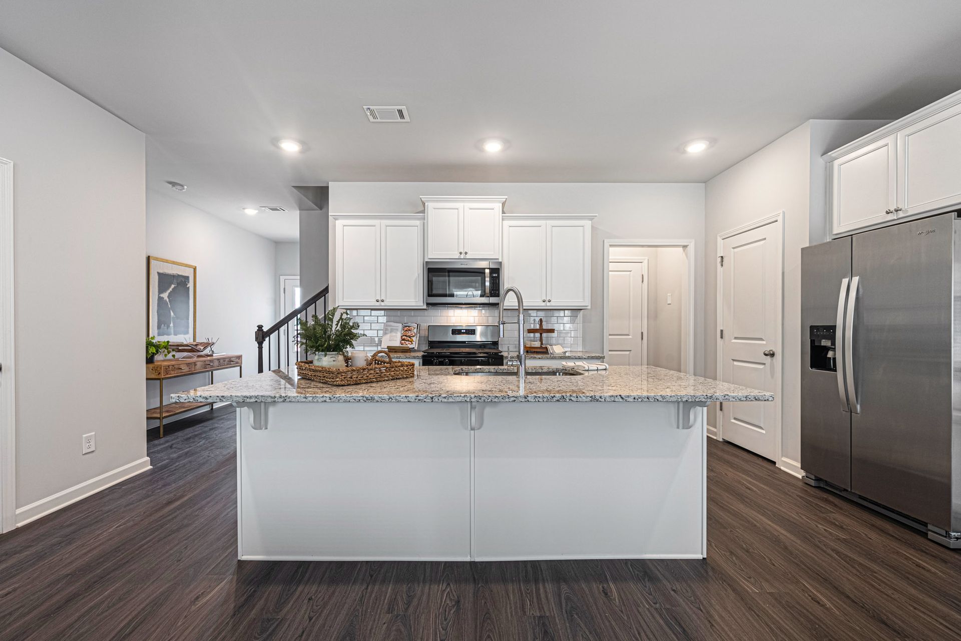 A kitchen with white cabinets , granite counter tops , stainless steel appliances and a large island at Collins Place.