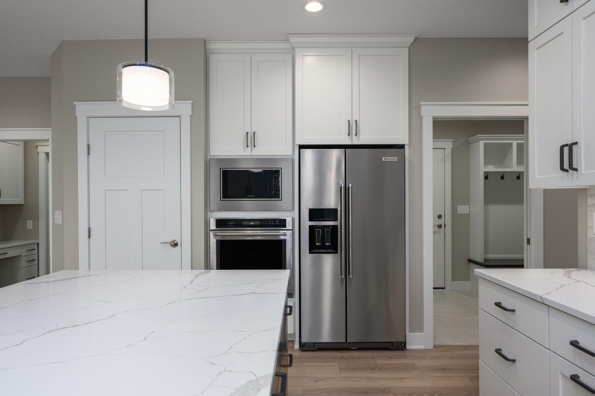 Modern white kitchen with stainless steel appliances and marble countertops.