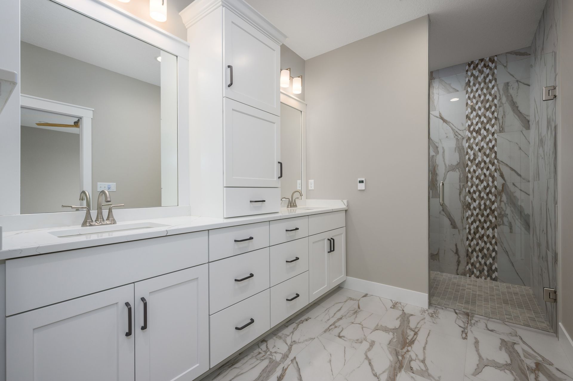 White bathroom with marble floor, large vanity with storage, and a tiled shower.