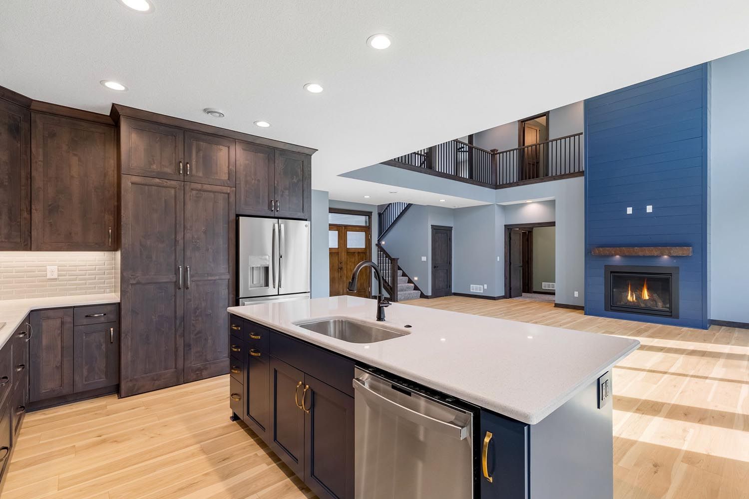 Modern kitchen with dark cabinets, island, and blue accent wall with fireplace.