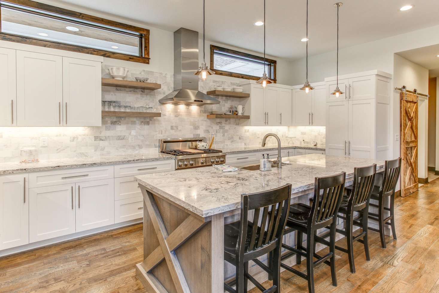Modern kitchen with white cabinets, island with stools, and wooden accents.