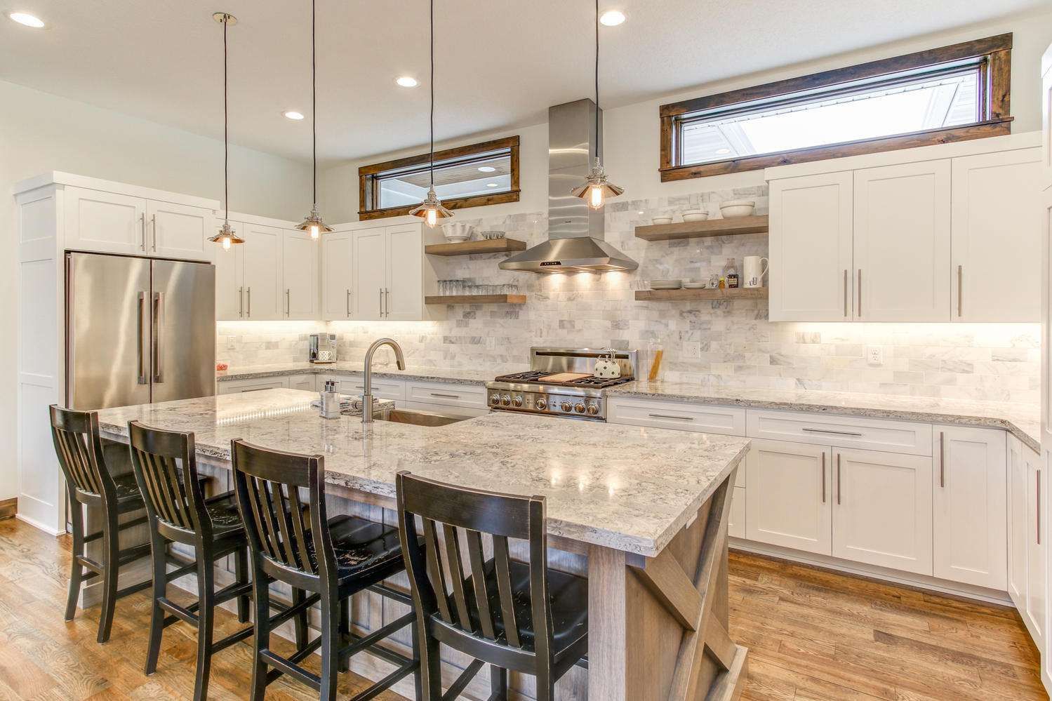 Modern kitchen with white cabinets, large island, and stainless steel appliances.
