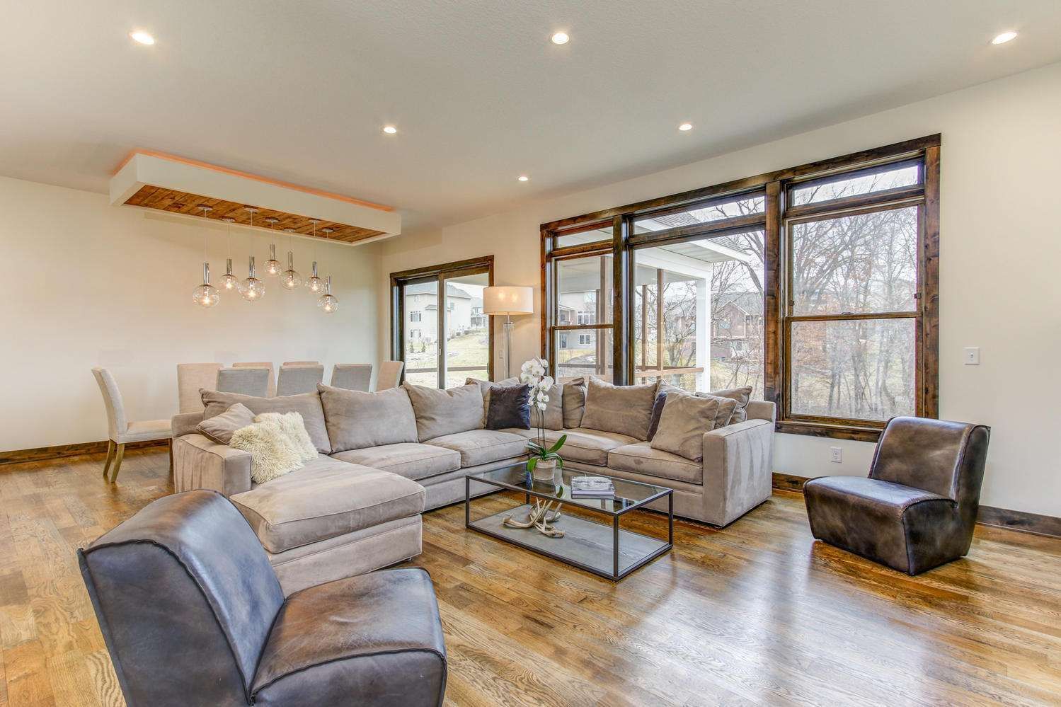 Spacious living room with sectional sofa, glass coffee table, and large windows.