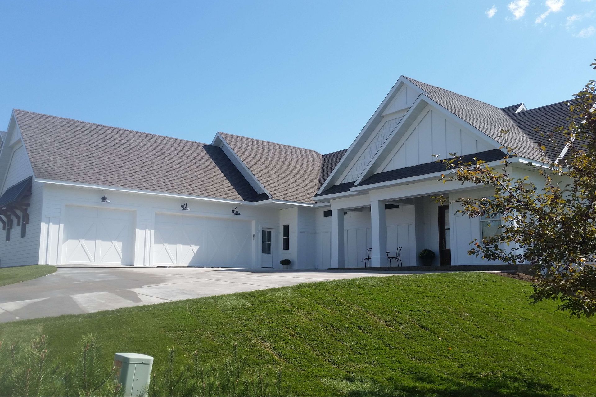 White house with a brown roof and a green lawn under a clear, blue sky.