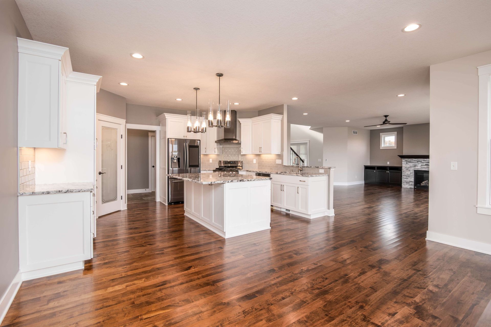 Spacious kitchen with white cabinets, island, and stainless steel appliances; hardwood floors.