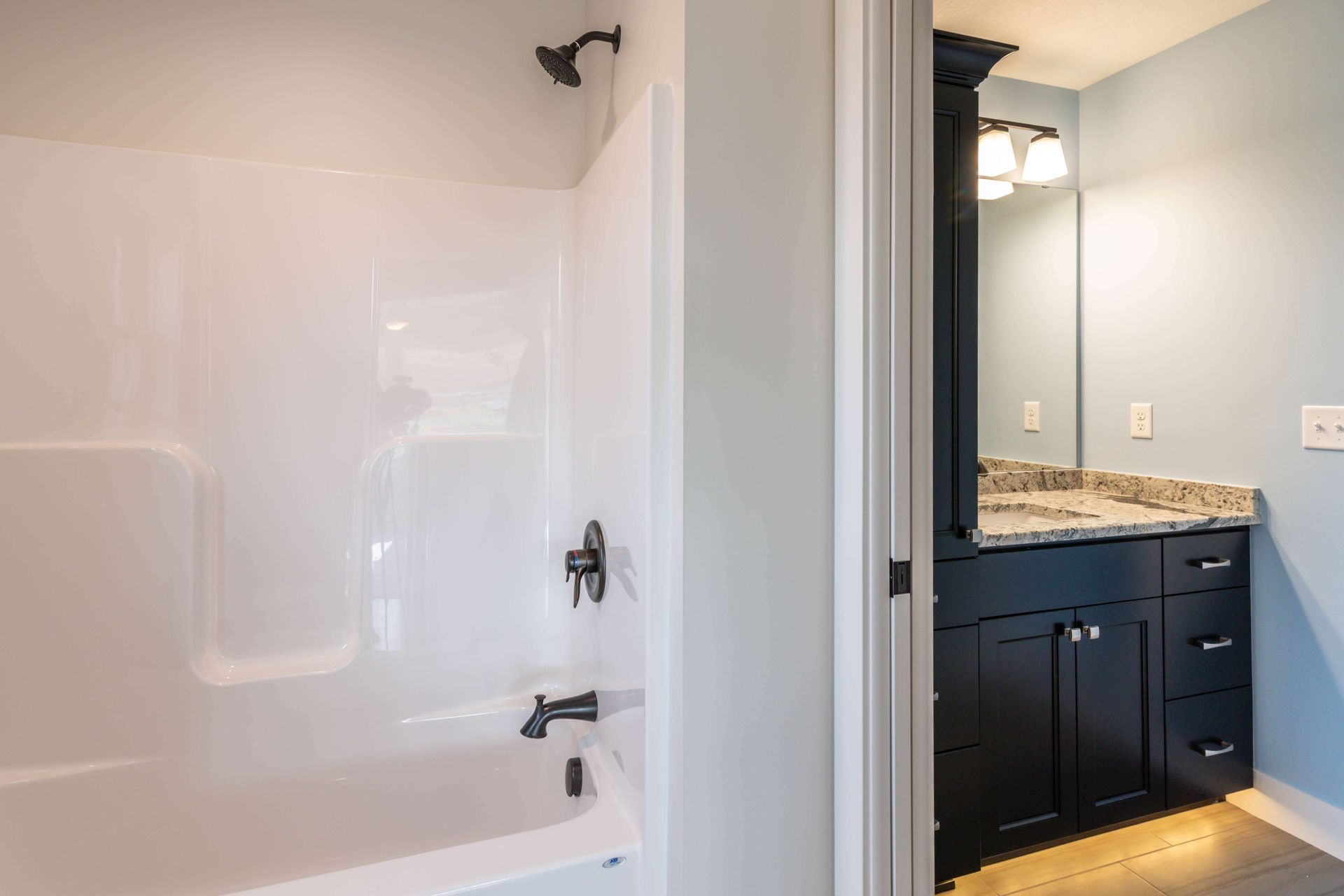 Bathroom interior with white shower/tub combo and dark vanity.