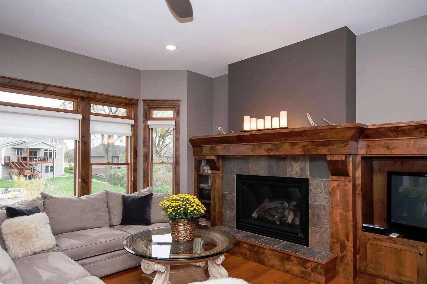 Cozy living room with a fireplace, sofa, and windows. Brown trim, gray walls, and natural light.