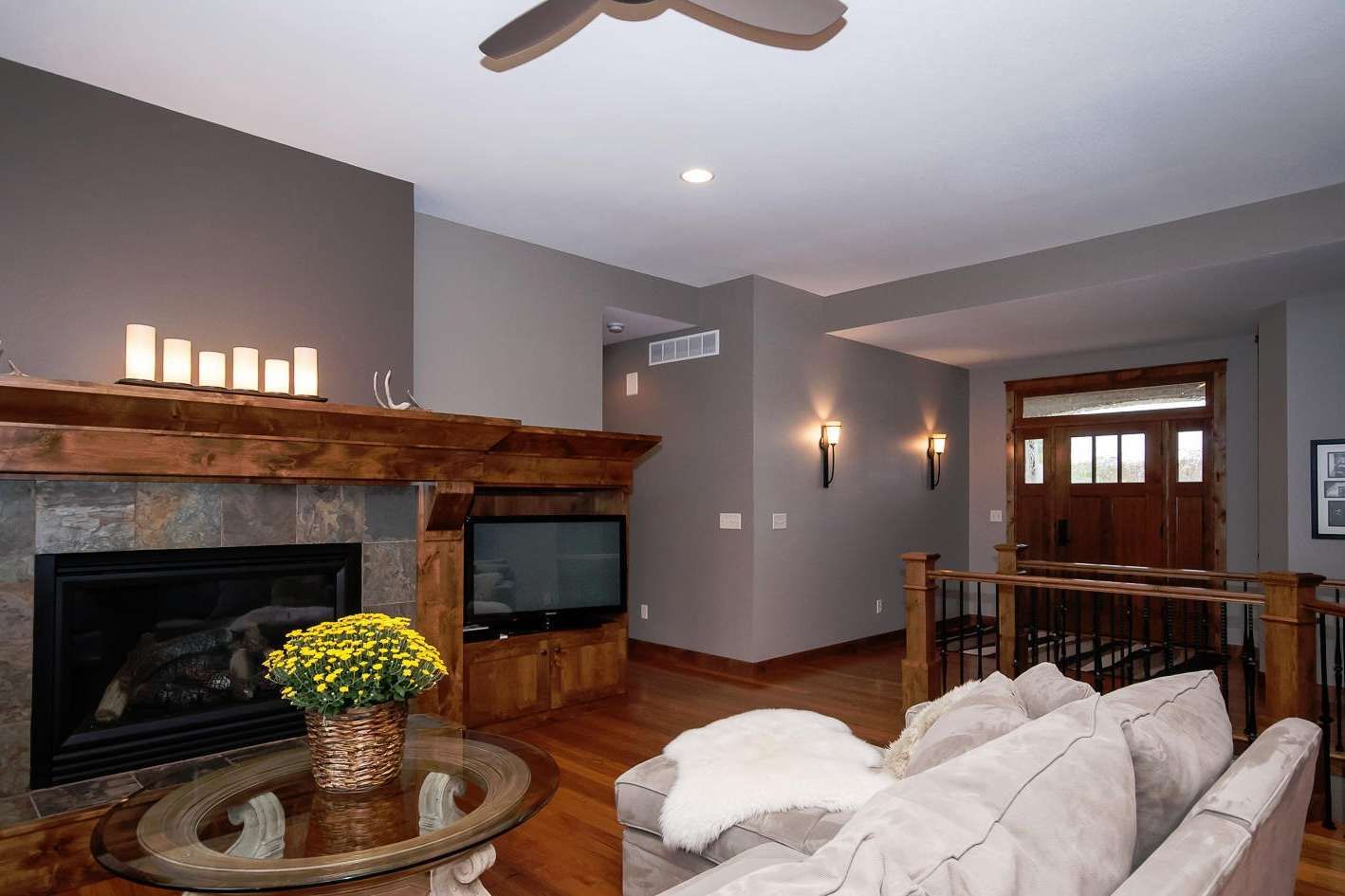 Living room with fireplace, TV, and couch. Dark gray walls, wood floors, and entrance visible.