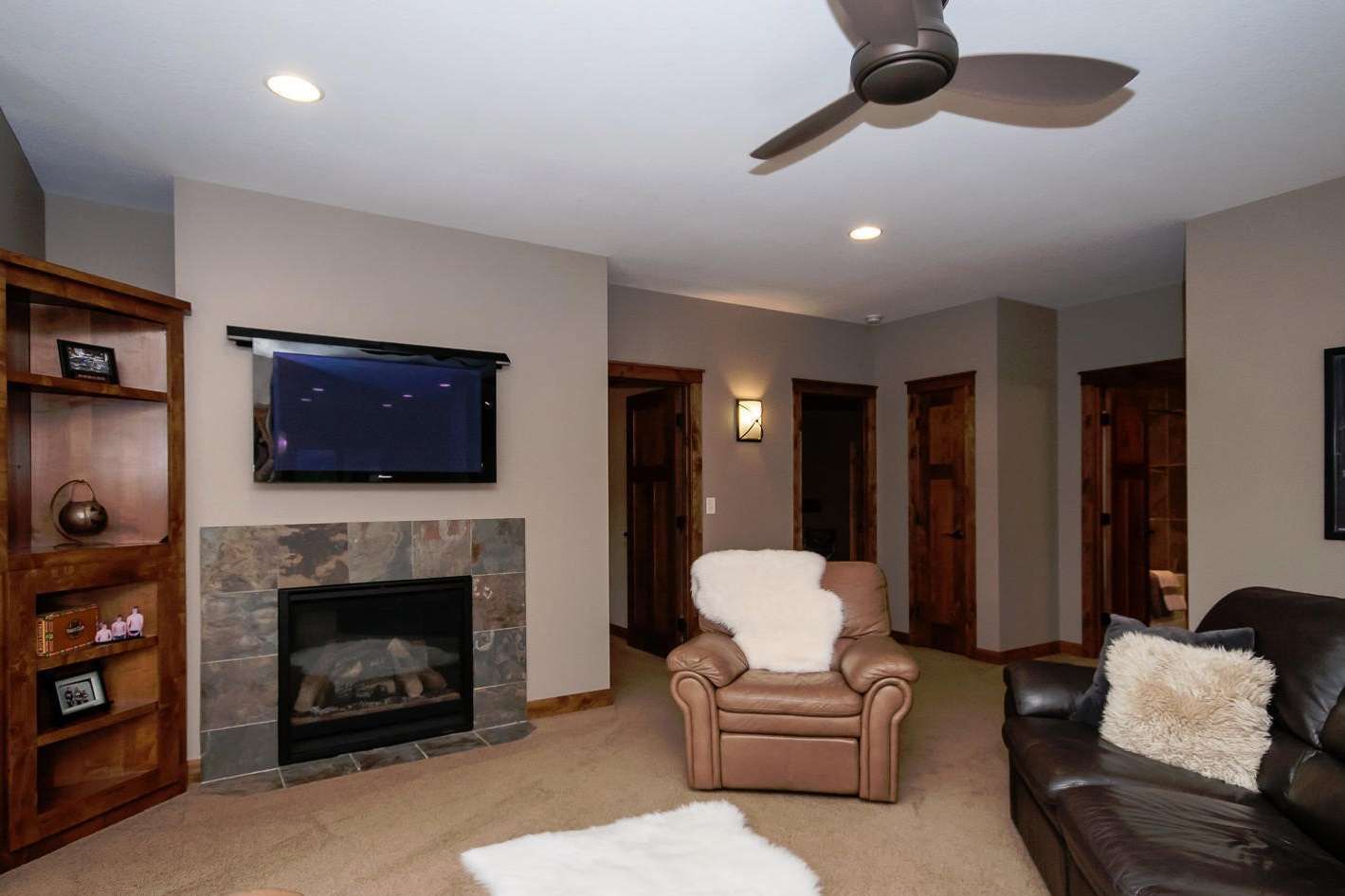 Cozy living room with fireplace, TV, brown leather furniture, and a sheepskin rug.
