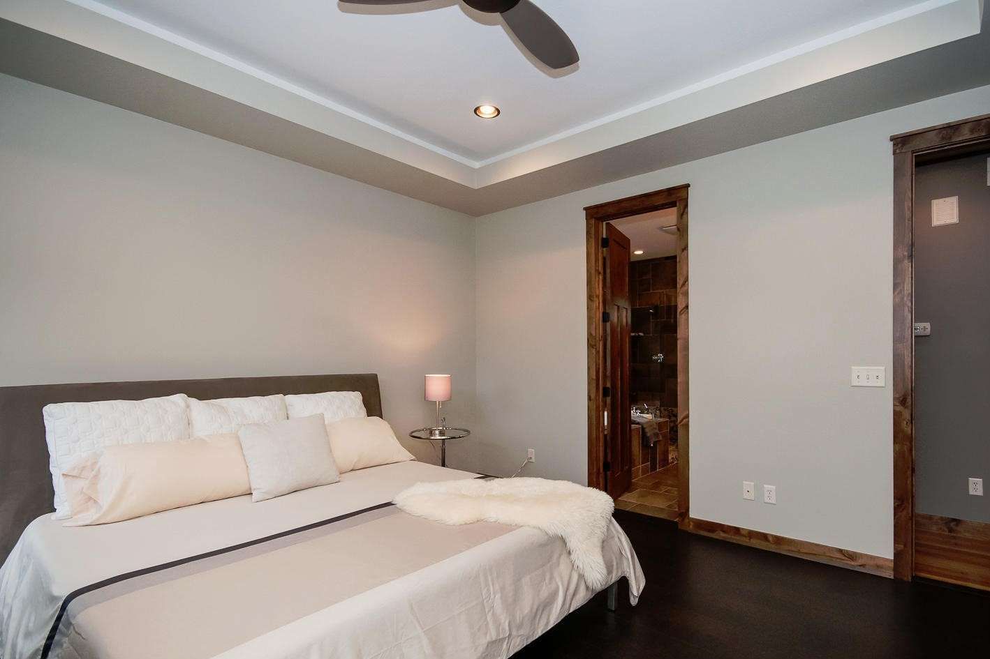 Bedroom with bed, dark wood floor, light gray walls, and walk-in closet.