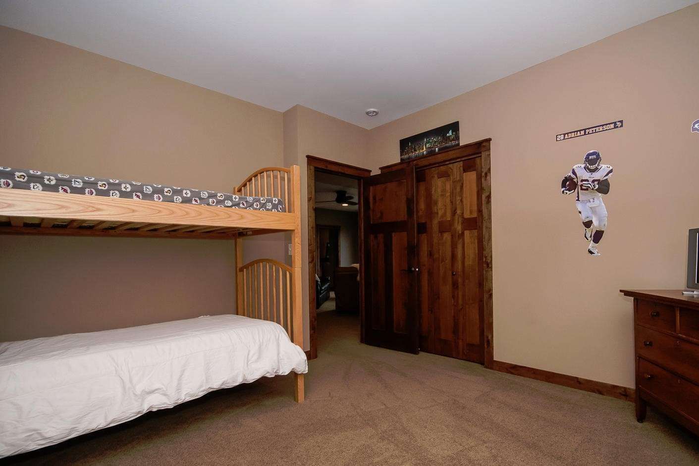 Bedroom with bunk beds, a wooden closet, and a football player decal on the wall.