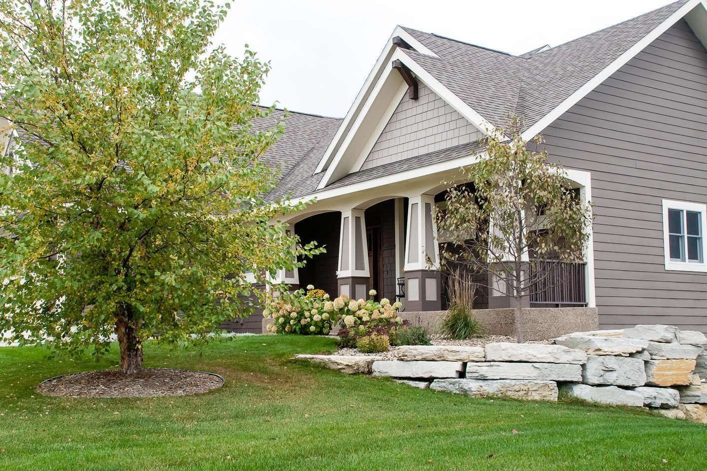 House exterior with gray siding, porch, and landscaping.