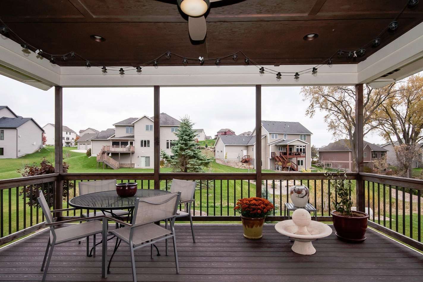 Screened-in porch with outdoor furniture, overlooking a neighborhood with green lawns and houses.