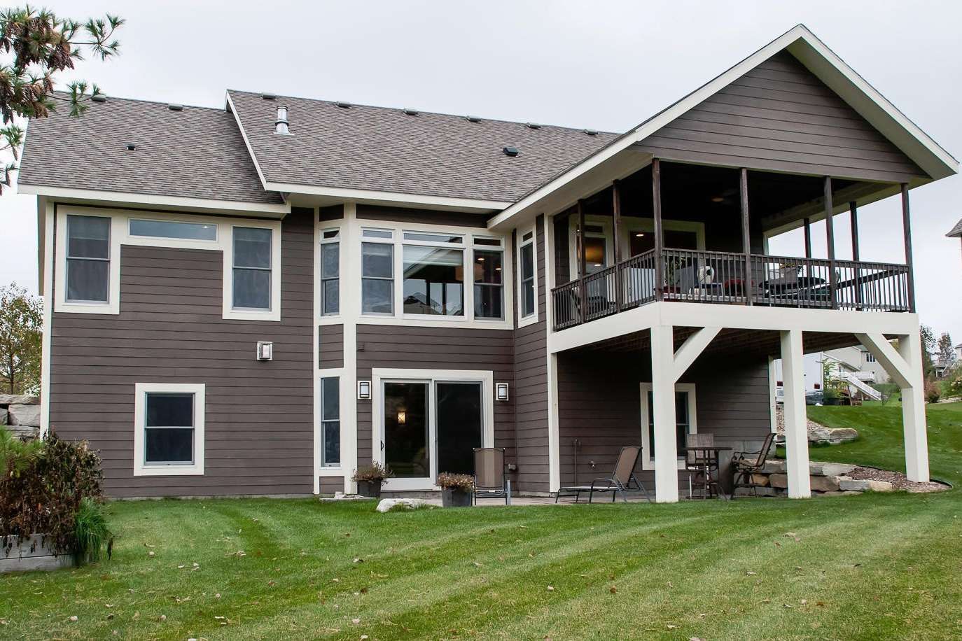 Brown house with a screened porch overlooking a green lawn.