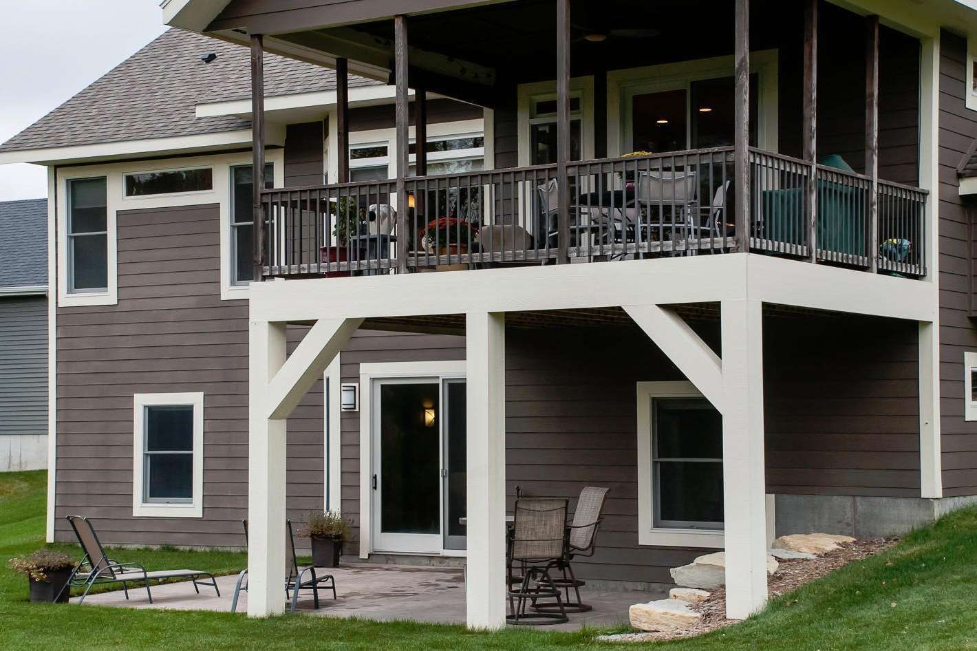 Two-story house with screened porch. Brown siding, white trim, outdoor furniture on patio and porch.