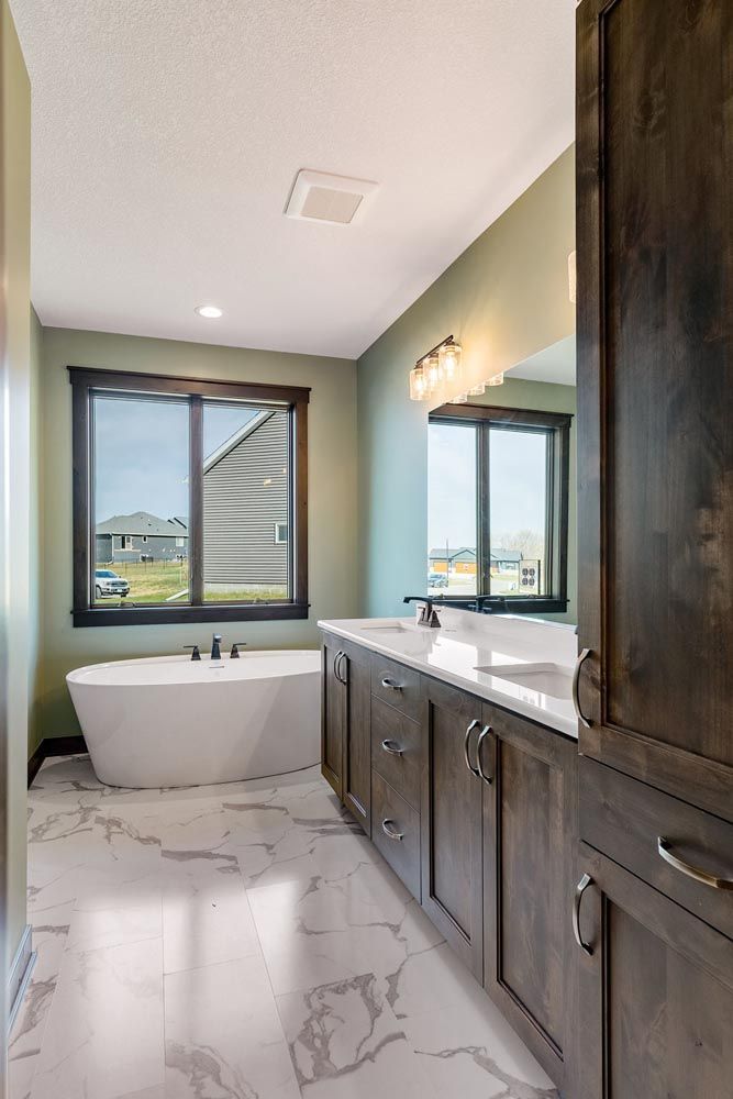 Modern bathroom with a white tub, marble floor, and dark wood cabinets.