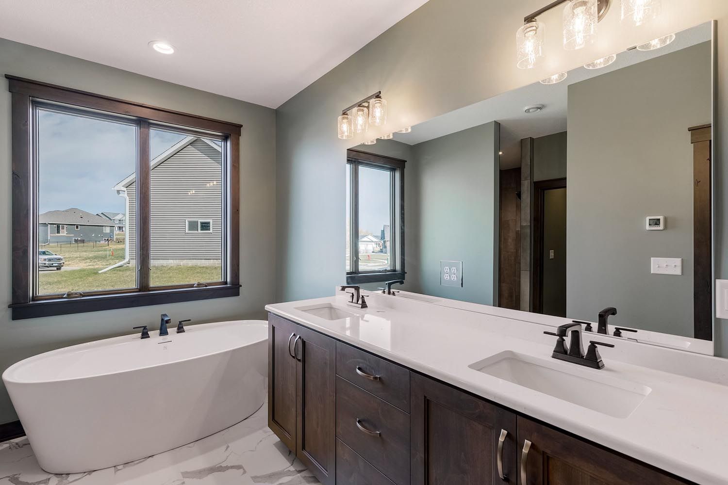 Modern bathroom with a white soaking tub, double vanity, and large mirror.