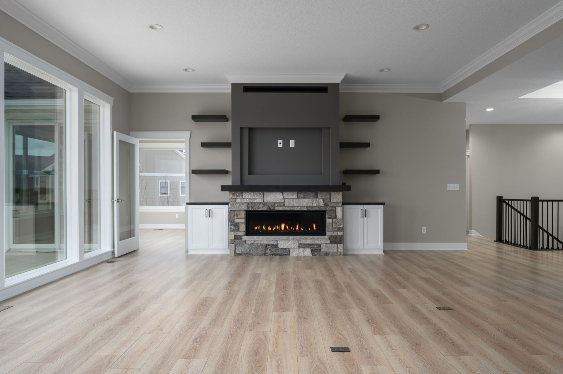 Living room with gray fireplace, stone surround, wood floors, and built-in shelves.