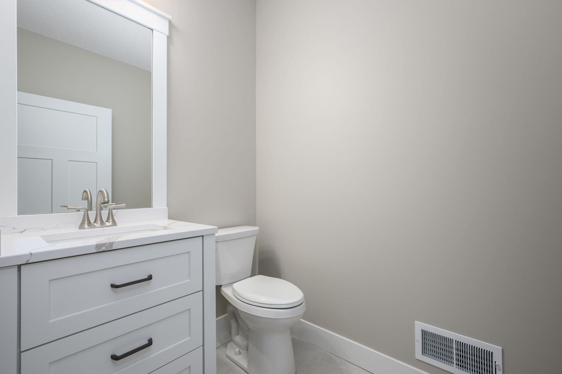 White bathroom with sink, mirror, and toilet against light gray walls.