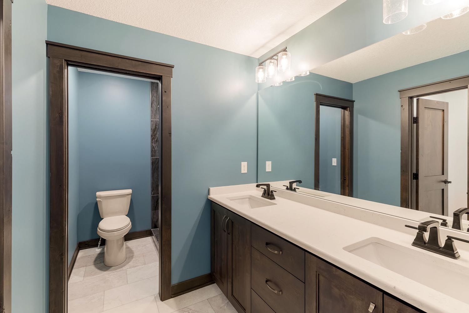 Bathroom with blue walls, dark brown cabinets, white countertop, and a toilet.